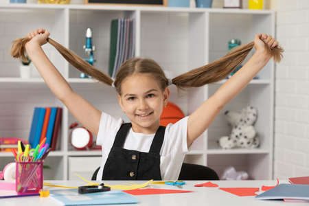happy kid having fun with long hair pony tail at school lesson in classroom wear uniform, schoolの写真素材