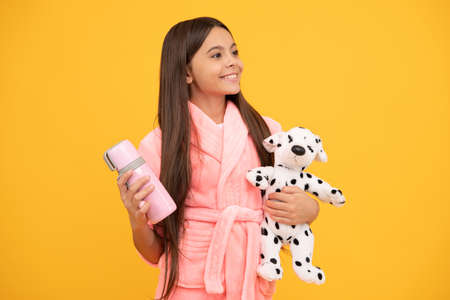 happy teen girl in home terry bathrobe with toy and thermo bottle, childhoodの写真素材