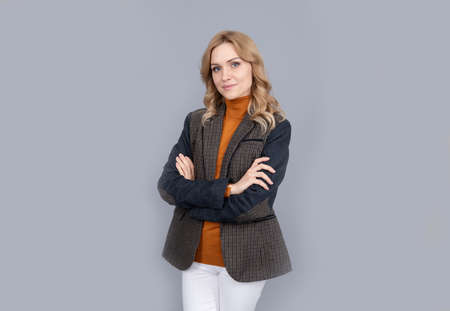cheerful blonde woman in business casual british jacket on grey background, confidenceの写真素材