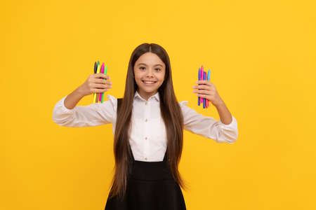 Happy school girl hold felt-tip pens yellow background, creativityの写真素材