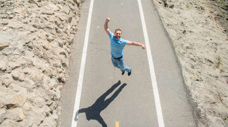 celebrating success. mature man jumping on road. full of energy. glad guy feel freedom.