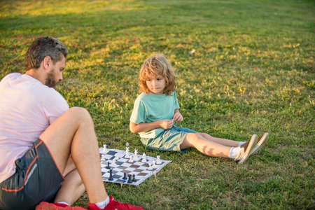 happy family of parent and son boy playing chess on green grass in park outdoor, chessの写真素材