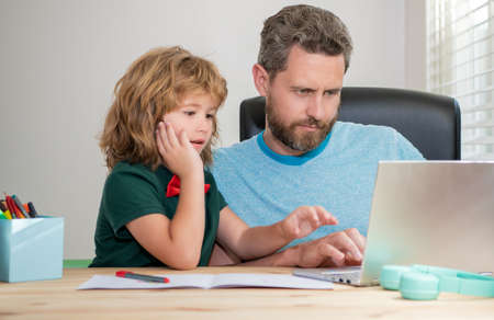 mature man teacher or dad helping kid son with school homework on computer, webinarの写真素材