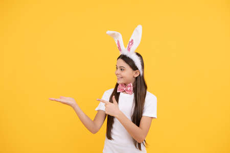 adorable kid presenting product. paschal spring holiday. copy space. happy teen girl wear bunny earsの写真素材