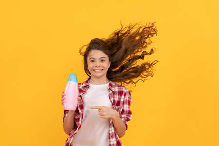 happy teen girl with shampoo bottle. shampooing hair in salon. child with conditioner.