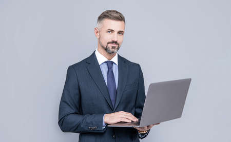 confident businessman man in businesslike suit typing on laptop, checking emailの写真素材