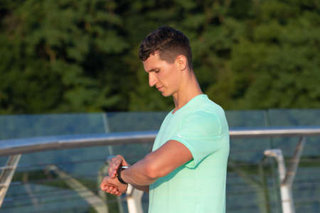 Analysing his result. Man check time on watch after workout. Exercise time. Sports timingの写真素材
