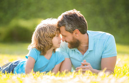 happy family of dad and son child relax in summer park green grass, charityの写真素材