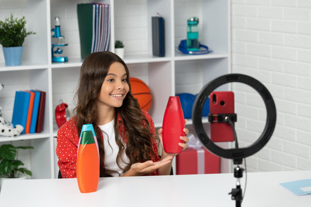 child presenting cosmetic product for teen. vlogger with shampoo bottle. making video blogの写真素材