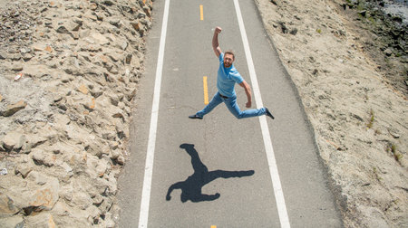 happy mature athletic guy jumping on road outdoor, emotionsの写真素材