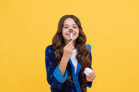 happy child girl in cozy bathrobe grooming with powder brush, skincare