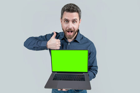 surprised mature man businessman presenting computer for copy space show thumb up, presentation.の写真素材