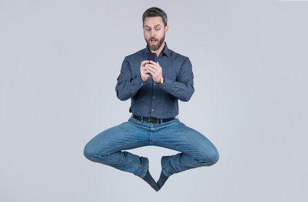 jumping man businessman chatting online on smartphone and meditating in yoga pose, business yoga.の写真素材