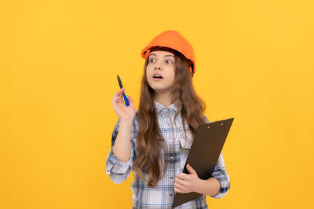 concentrated child worker wear hardhat hold clipboard. childhood development.の写真素材