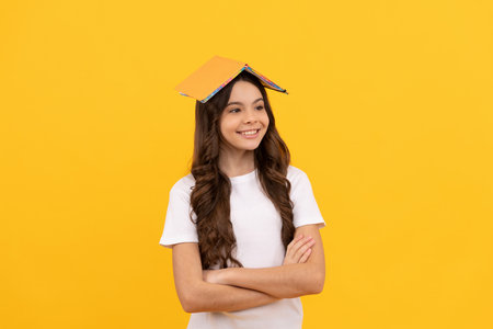 smiling school teen girl ready to study with planner on head, educationの写真素材