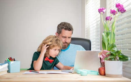 back to school. comcentrated father and son use computer at home. family blog.の写真素材