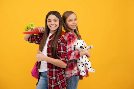 happy teen girls in casual checkered shirt carry backpack toy and penny board, skateboardの写真素材