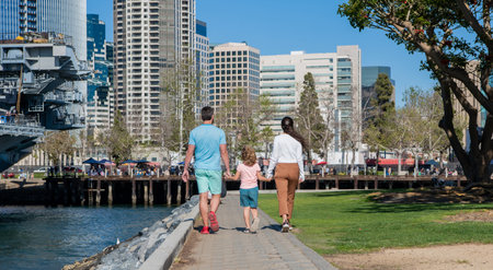 back view of young mother and father walking in park with child, parentingの写真素材