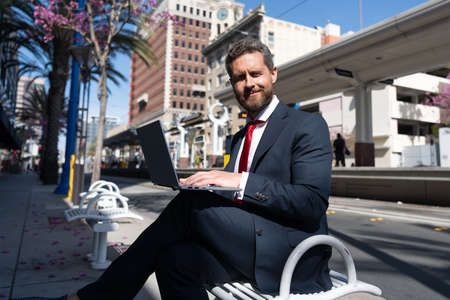 cheerful professional executive hold computer outdoor. boss with modern wireless laptopの写真素材