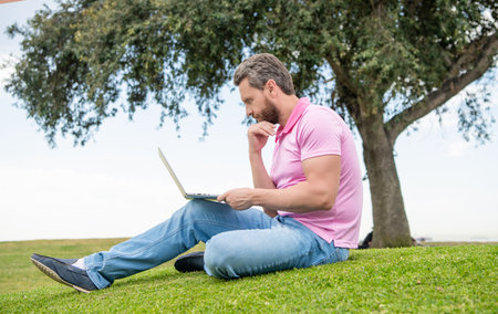 busy guy check email on computer relaxing on grass, online educationの写真素材