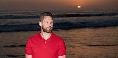 caucasian guy on sunrise beach. bearded man in shirt. summer fashion style.の写真素材