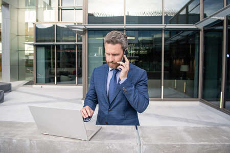 successful businessman in formal suit working online on laptop and speak on phone, communication.の写真素材
