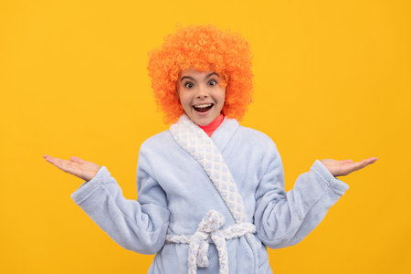 surprised teen girl in fancy orange wig hair wear home bathrobe presenting product, choiceの写真素材