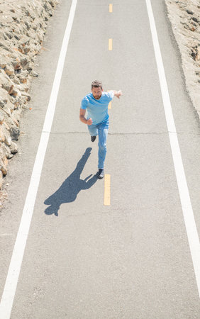 mature man running on road. sport activity. full of energy. guy feel freedom. hurry up.の写真素材