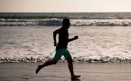 sport athlete run fast to win in the ocean. morning workout activity. healthy man running on beach.の写真素材