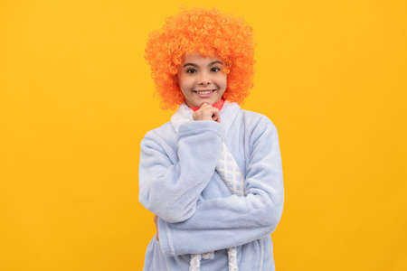 cheerful child in fancy orange wig hair wear home bathrobe, morningの写真素材