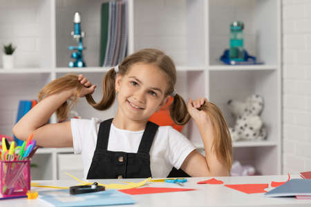 cheerful child having fun with long hair pony tail at school lesson wear uniform, childhood.の写真素材