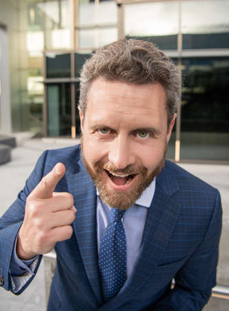 happy handsome entrepreneur in businesslike suit outside the office point finger, emotionsの写真素材
