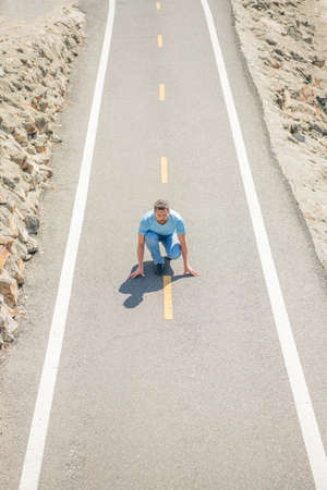 mature man at start on road ready to run, runnerの写真素材