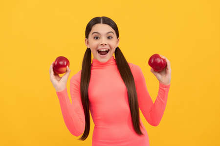 amazed teen girl with red apple on yellow background, detoxの写真素材