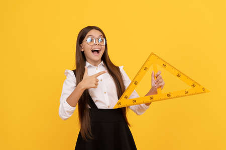 amazed child in school uniform and glasses hold mathematics triangle for measuring, trigonometryの写真素材