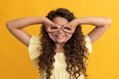 funny kid with long curly hair and perfect skin making faces, have funの写真素材