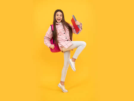 tween child carry school bag. childhood and education. energetic student hold notebooks runningの写真素材
