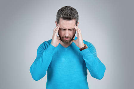 mature man with beard has heacache or show concentration on grey background, concentrationの写真素材