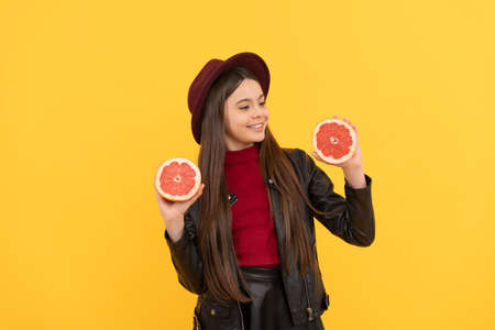 happy teen girl in hat and leather jacket hold cut grapefruit, vitaminの写真素材