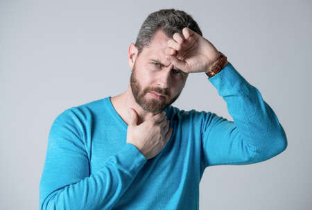 mature man with beard has heacache suffer from headahce on grey background, malaise