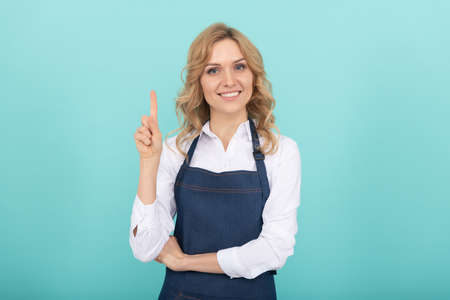 inspired woman in apron pointing finger. housewife express happiness. positive emotions.の写真素材