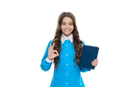 Happy primary school pupil hold library book showing OK sign isolated on white, knowledge dayの写真素材