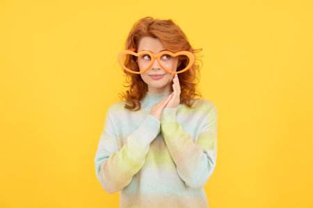 happy redhead woman wear funny party glasses on yellow background, partyの写真素材