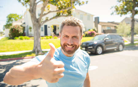 emotional mature guy gesturing. happy man outdoor on new house background.の写真素材