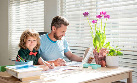 bearded dad writing school homework with his child son in classroom, childhoodの写真素材