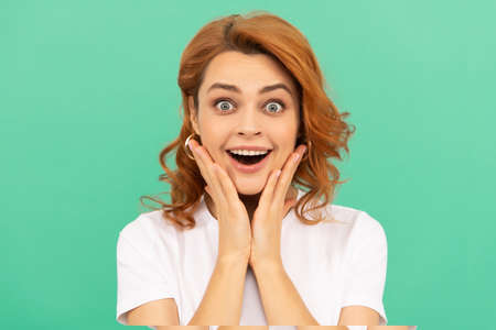 surprised redhead girl with curly hair and healthy skin on blue background, surpriseの写真素材