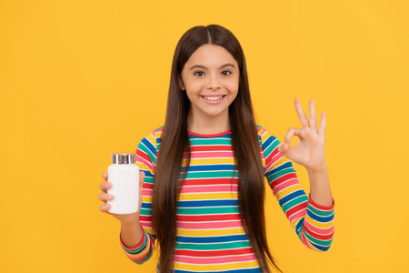 happy teen girl presenting natural food additives or vitamin pills in jar, okの写真素材