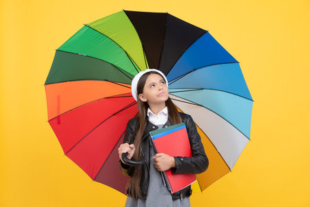 happy girl in glasses hold notebook. education. teen child under colorful parasol.の写真素材