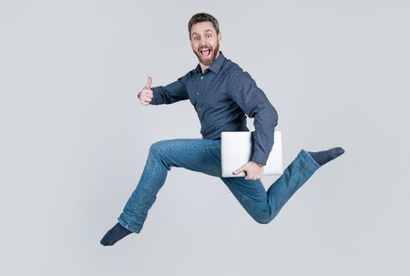jumping man running while working online on laptop hurry up for shopping show thumb up, success.の写真素材