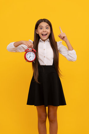 inspired with idea child with alarm clock. school kid in uniform showing time.の写真素材